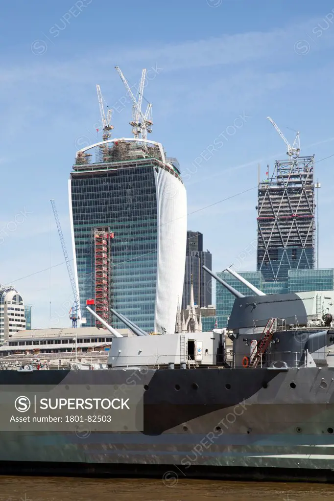 Walkie-Talkie - 20 Fenchurch Street, London, United Kingdom. Architect: Rafael Viñoly, 2013. Walkie-Talkie tower topping out with the 'Cheese-grater' rising behind to the right. HMS Belfast is in the for ground with her guns pointing upwards.
