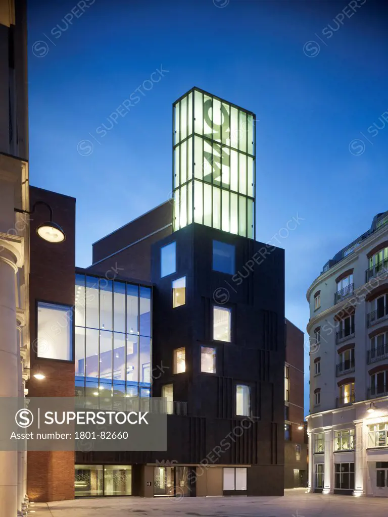 MAC, Belfast, Belfast, United Kingdom. Architect: Hall McKnight, 2012. General exterior elevation with glazed tower and lit interior on top of stone facade.