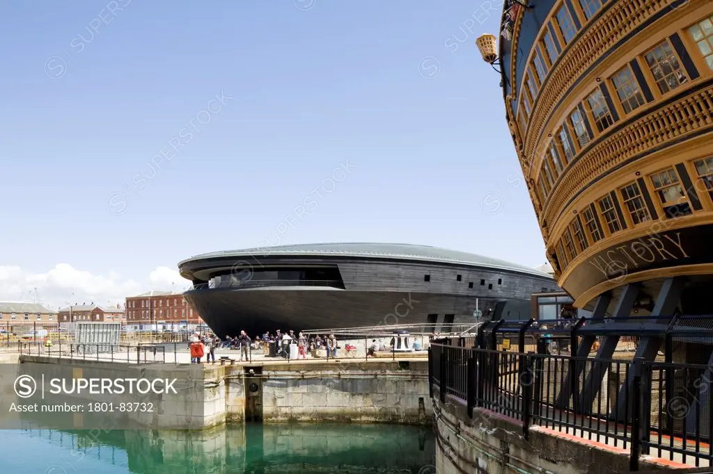 The Mary Rose Museum, Portsmouth, United Kingdom. Architect: Wilkinson Eyre Architects , 2013. External view of museum with The Victory in foreground.