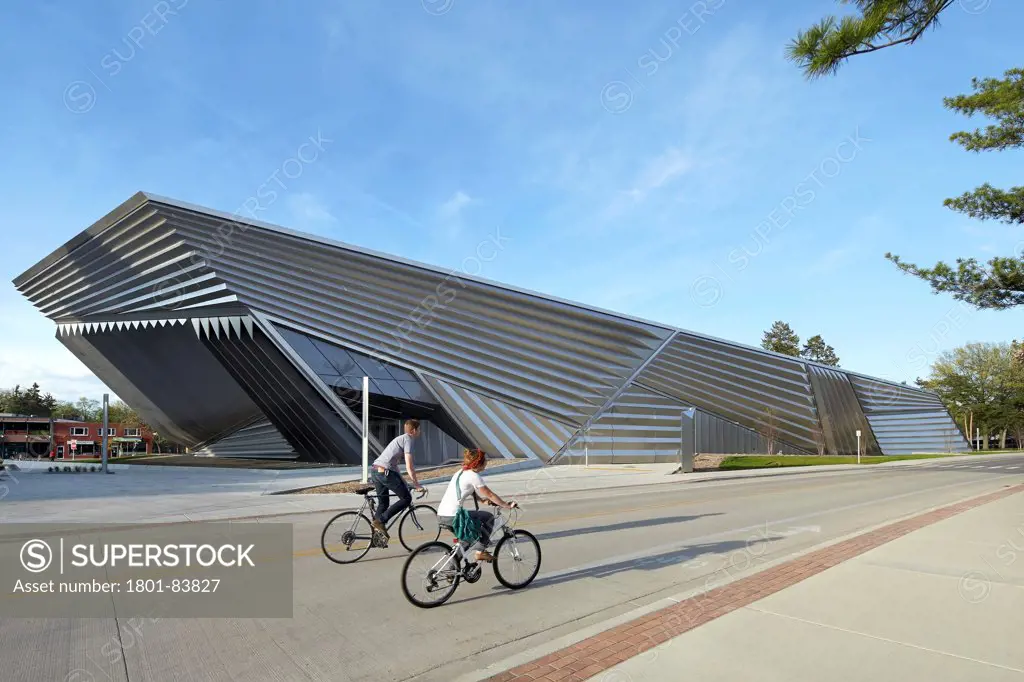 Eli & Edythe Broad Art Museum, Lansing, United States. Architect Zaha Hadid Architects, 2013. Campus paths with cyclists and museum in background.