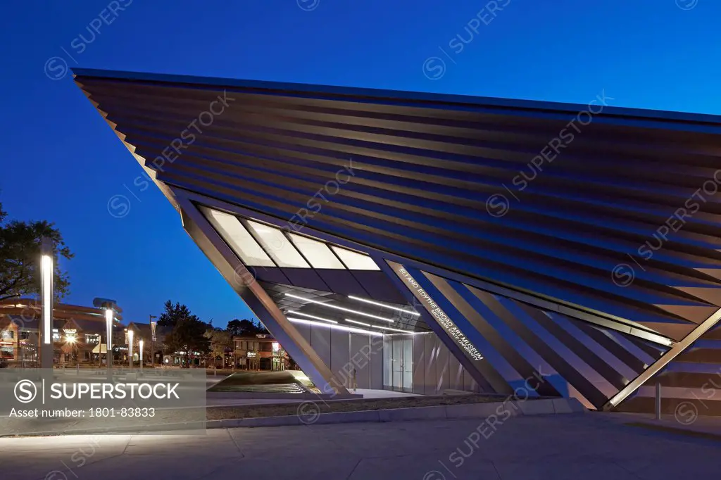 Eli & Edythe Broad Art Museum, Lansing, United States. Architect Zaha Hadid Architects, 2013. Perspective of angular steel skin and campus in background at dusk.