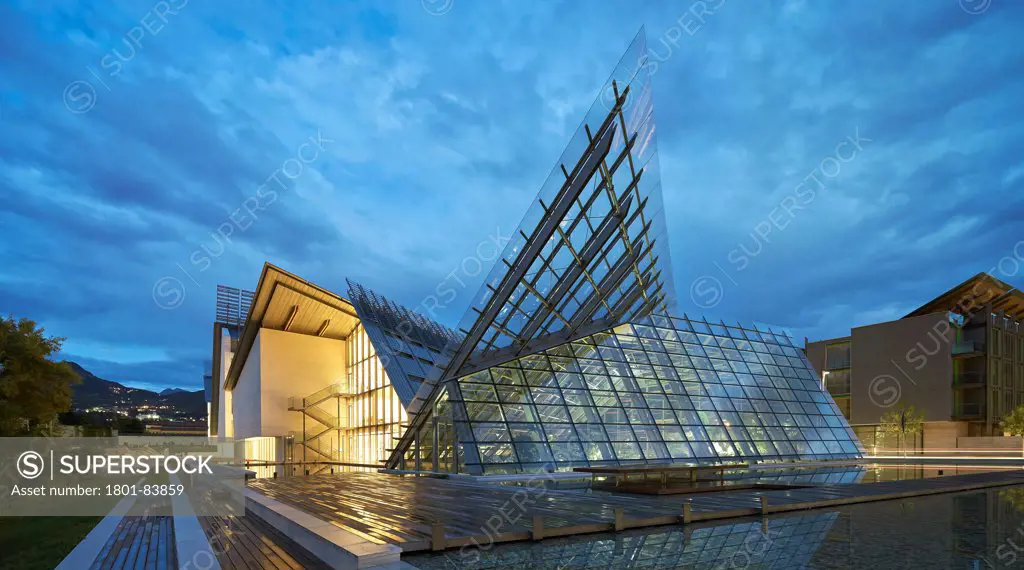 MUSEScience Museum, Trentino, Italy. Architect Renzo Piano Building Workshop, 2013. Side elevation with illuminated interior at dusk.
