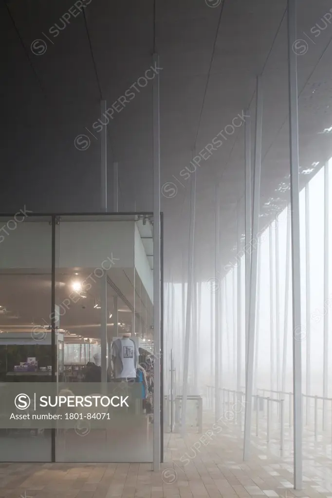Stonehenge Visitor Centre, Amesbury, United Kingdom. Architect Denton Corker Marshall LLP, 2013. Corner of shop roof supported by irregular columns in fog.