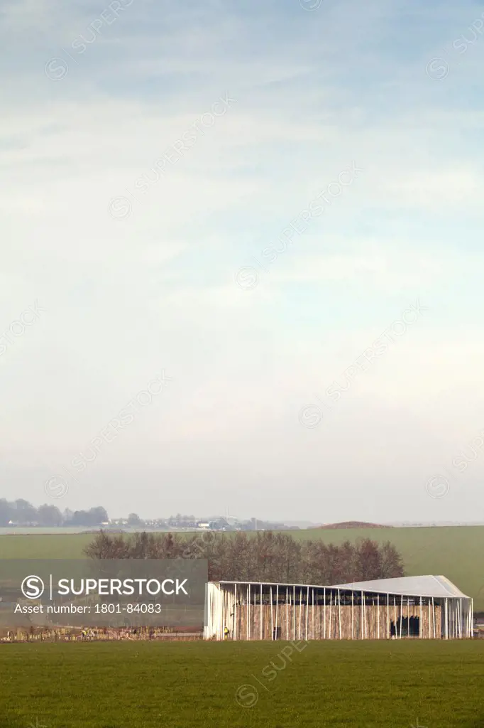 Stonehenge Visitor Centre, Amesbury, United Kingdom. Architect Denton Corker Marshall LLP, 2013. Contextual view from South in landscape with tumuli burial mounds.
