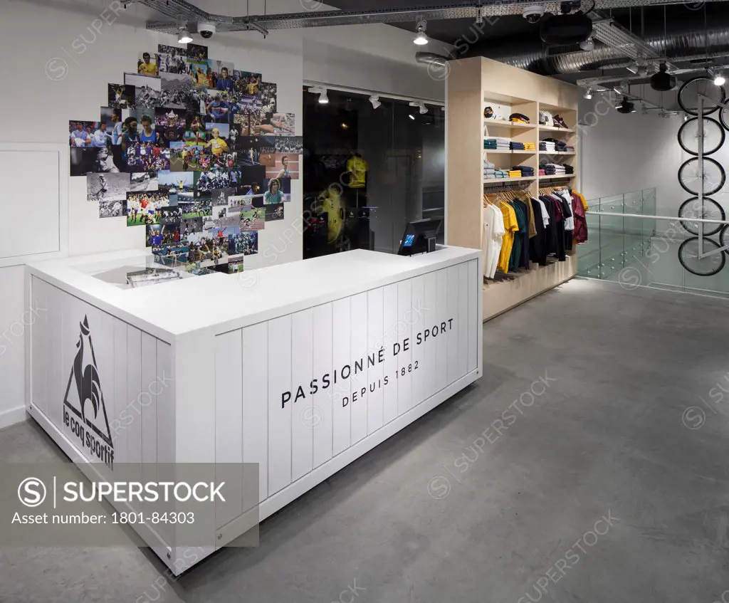 Le Coq Sportif London -FlagshipStore, London, United Kingdom. Architect Studio Oscar, 2013. Store counter and til with a rotating advertising board on the front and side. Merchandise in the background.