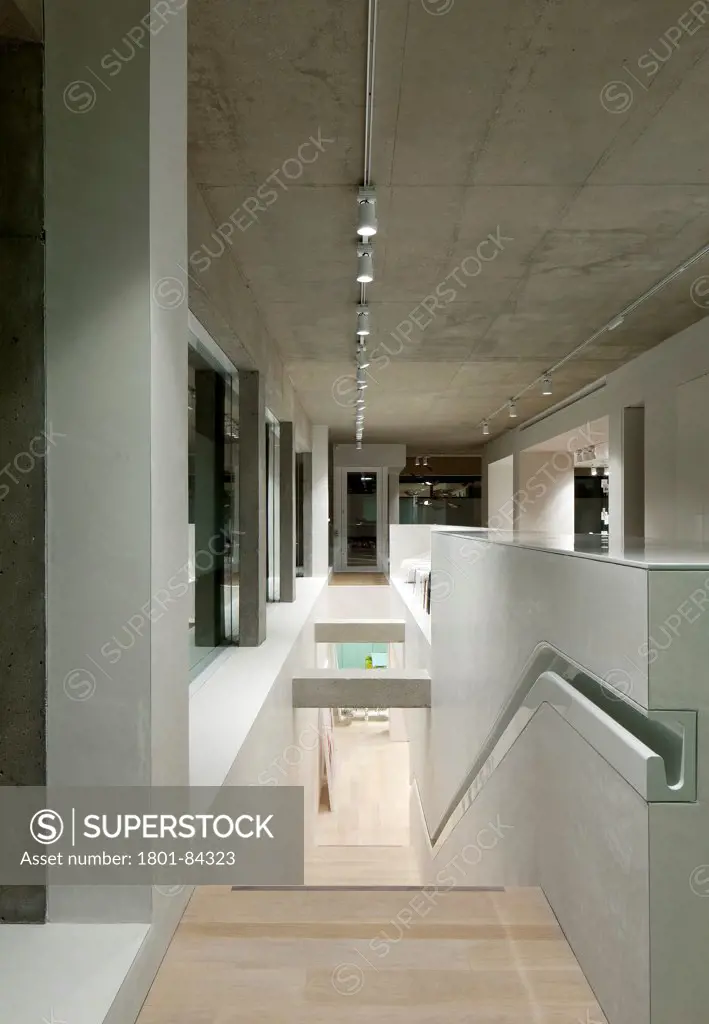 Arper London Showroom, London, United Kingdom. Architect 6A, 2012. View of stairswith fine concrete columns looking down into basement, ceramic handrail runs down the right of the staircase.