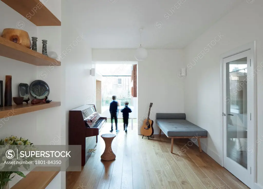 Power House, London, United Kingdom. Architect Paul Archer Design, 2013. Two children looking over into the kitchen area below. A glass panel at the end wall of the first floor music/playroom creates a balcony overlooking the main space.