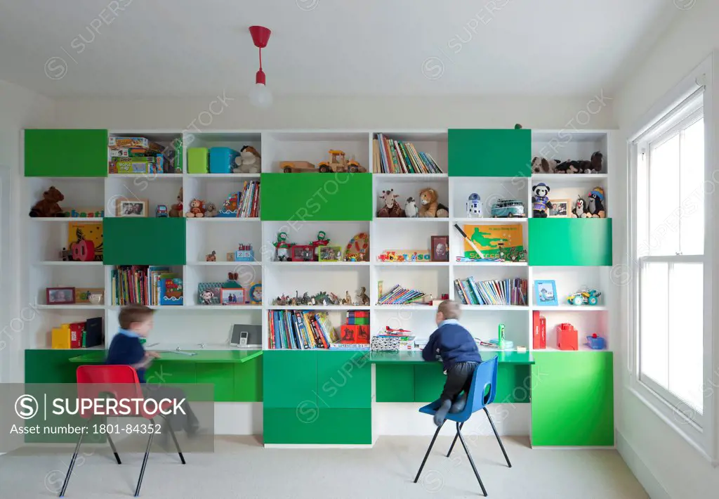 Power House, London, United Kingdom. Architect Paul Archer Design, 2013. Two children play on their fold down desks. The colour scheme of green hues, providing a strong counterpoint to the natural wood used throughout the house.