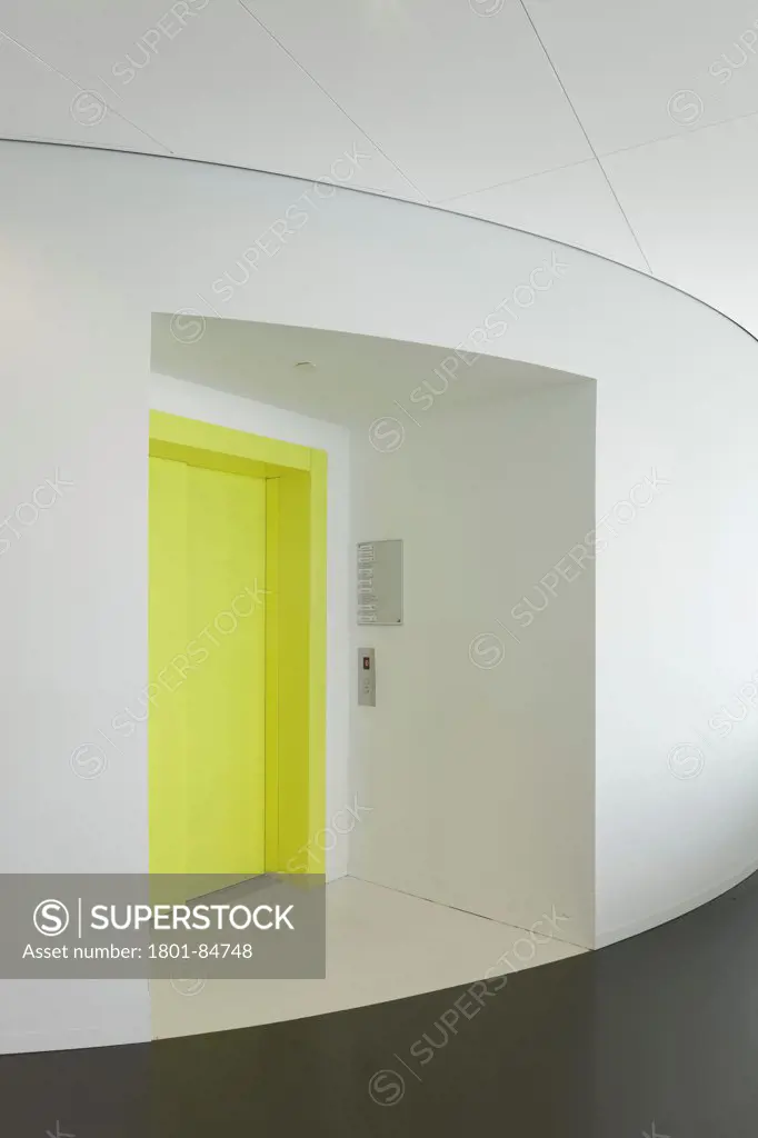 Entrance to lift with yellow door against curved white wall in office area