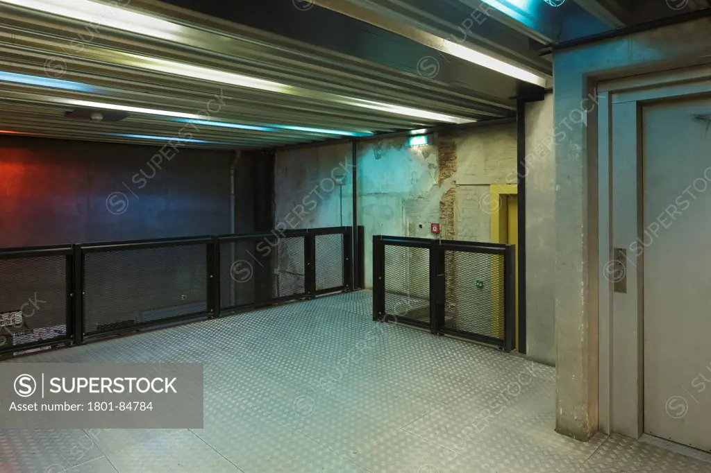 Hallway outside main venue with coloured lighting, concrete walls and metal flooring