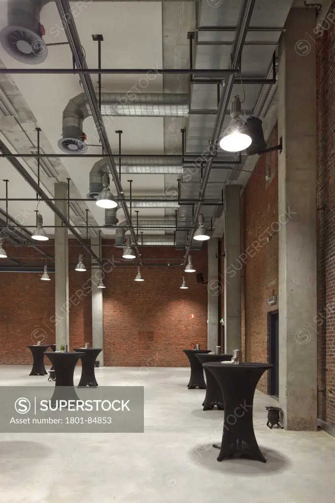 Banqueting hall with concrete pillars, exposed metal pipework and brick walls