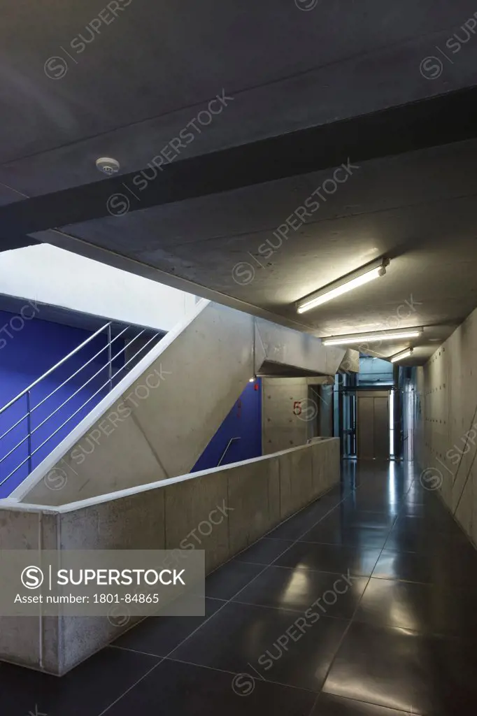 Concrete walls and staircase on upper floor with blue painted elements and black gloss floor