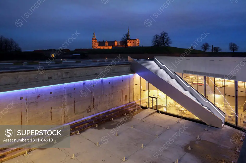 Illuminated exterior staircase down to dry dock with Kronborg Castle in distance at dusk