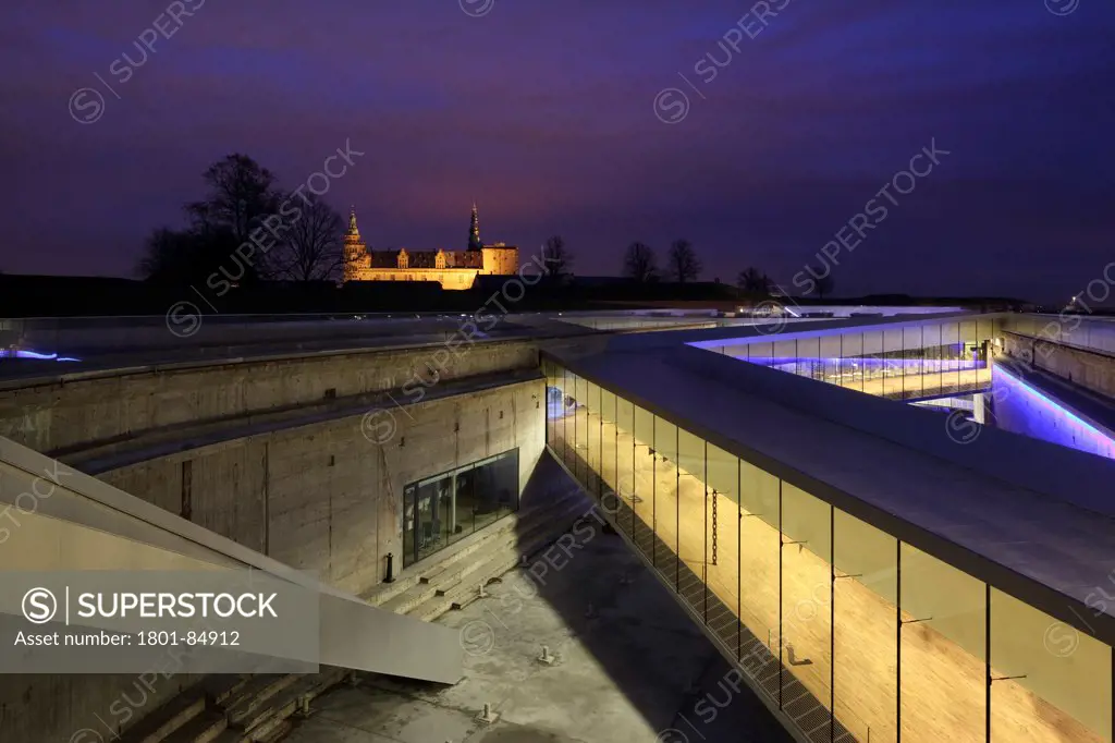 Illuminated walkways above dry dock with Kronborg Castle in distance at dusk