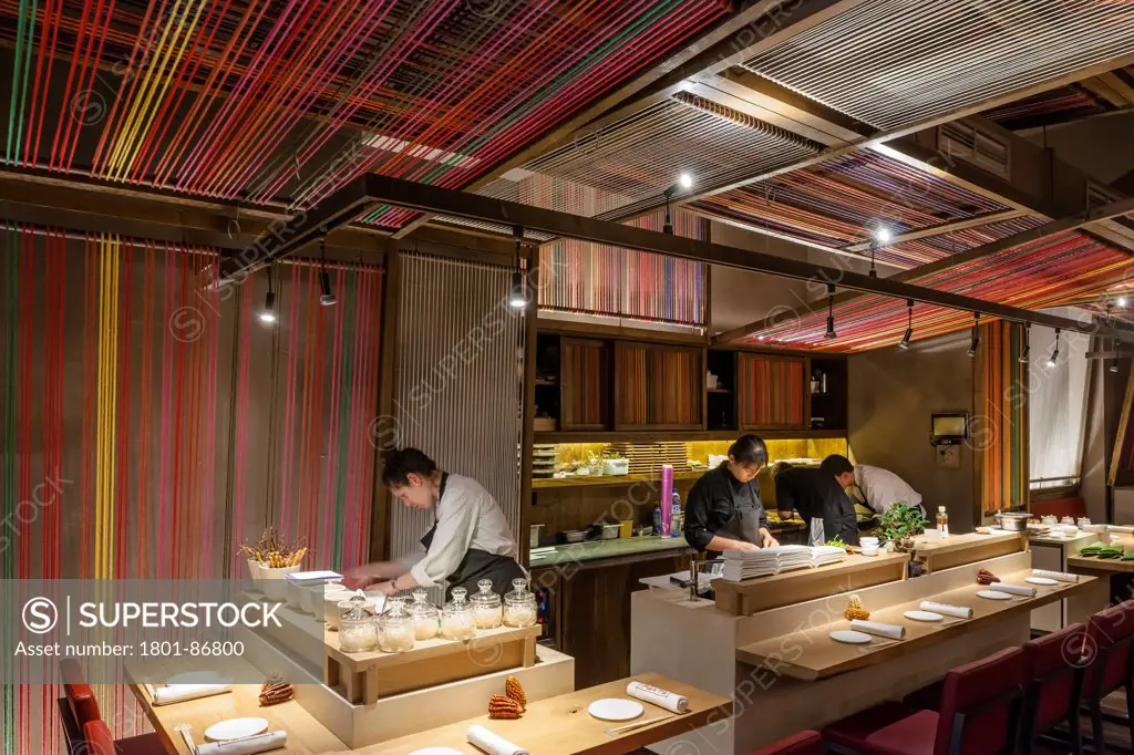Patka Restaurant, Barcelona, Spain. Architect El Equipo Creativo, 2013. View along bar counter with chef at work.