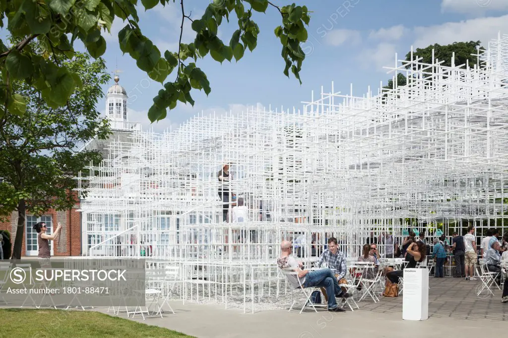 Serpentine Pavilion 2013, London, United Kingdom. Architect Sou Fujimoto, 2013. View with gallery in background and cafe.