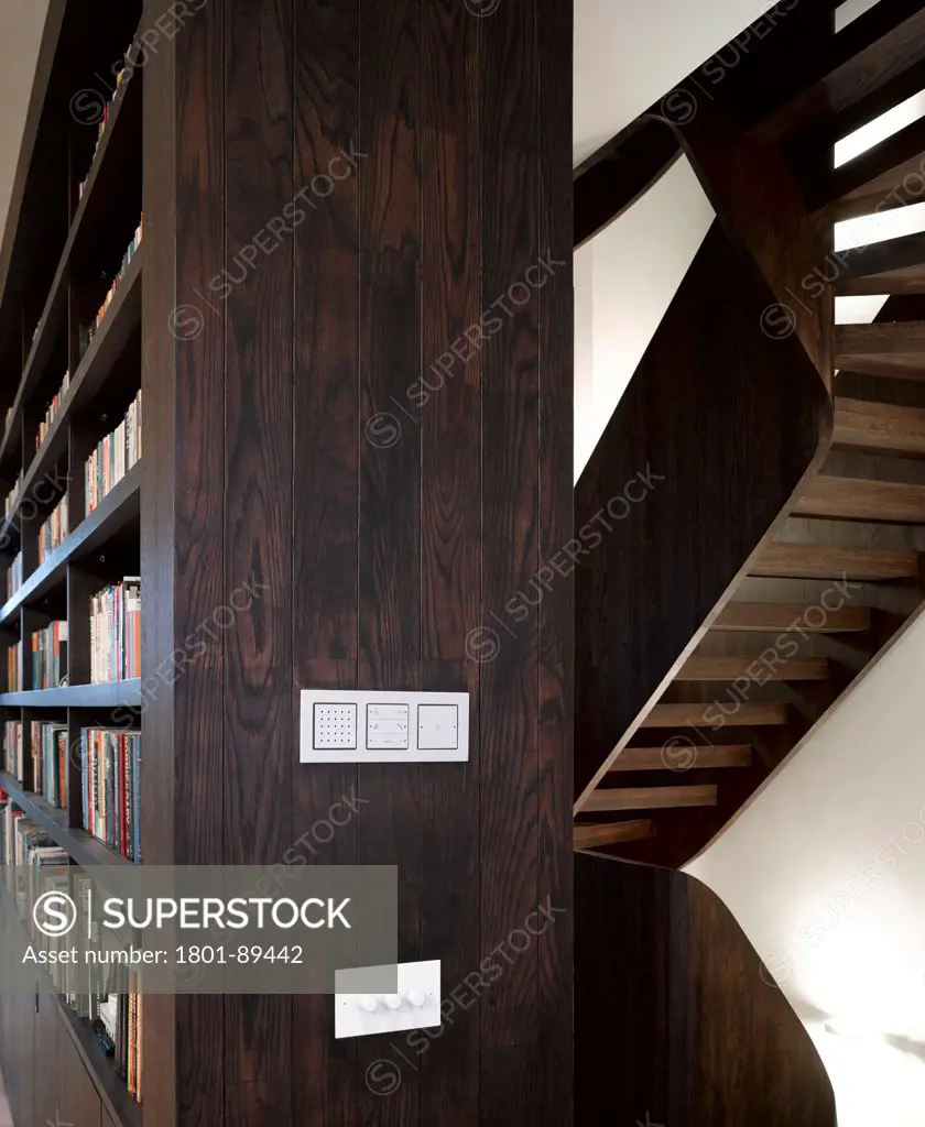 St Johns' Orchard, London, United Kingdom. Architect: John Smart Architects, 2013. Interior View showing bookshelves with staircase in background.
