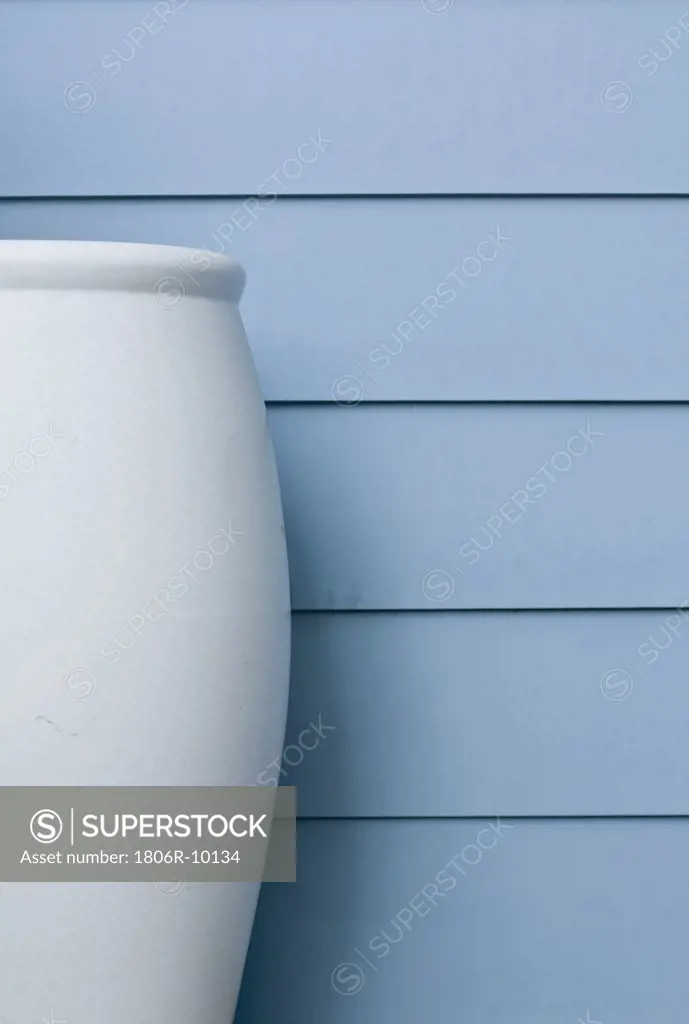 Large blue vase along blue siding