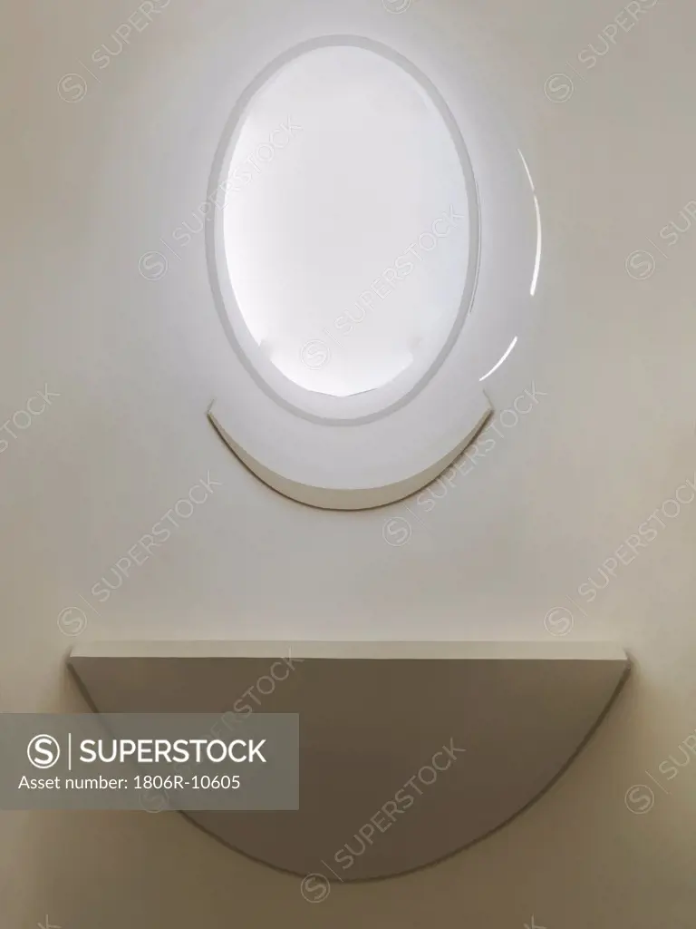 Architectural detail of oval shaped window with shelf on off white wall. 07/20/2009
