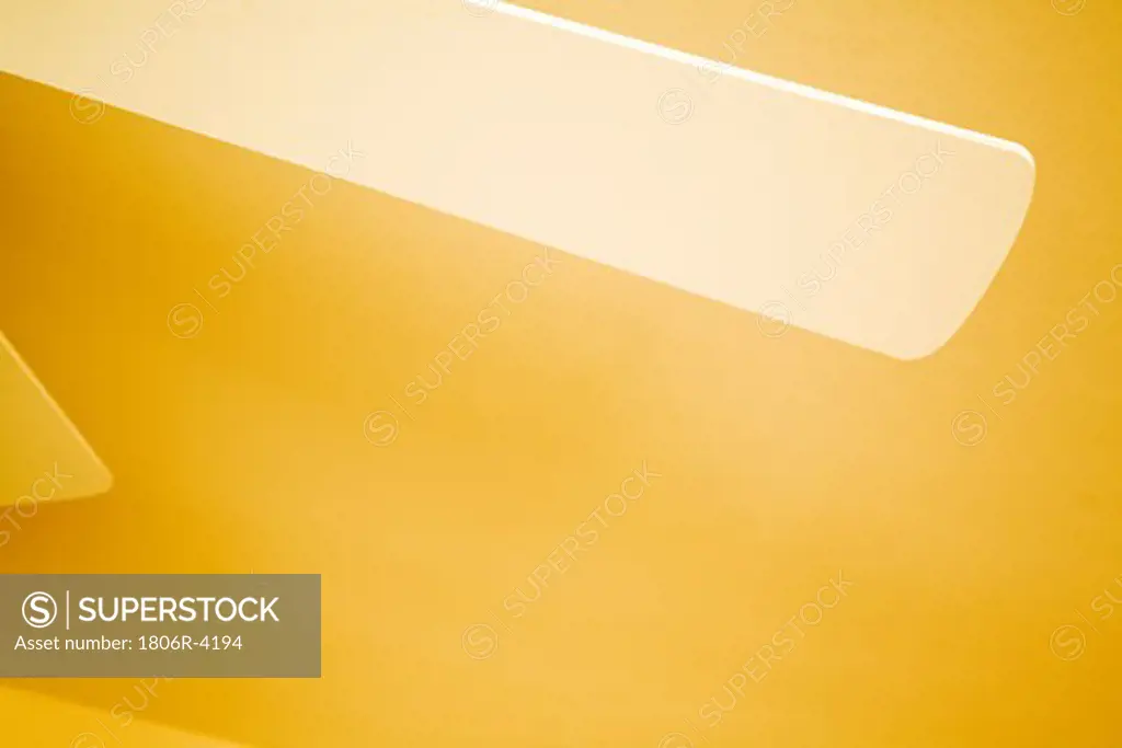 Blades of White Ceiling Fan against Yellow Ceiling