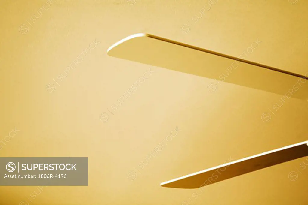 Blades of White Ceiling Fan against Yellow Ceiling