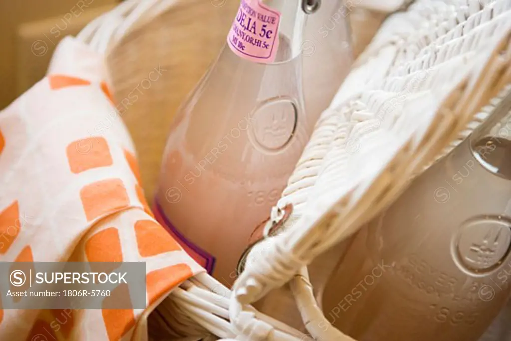 Bottle of pink lemonade in picnic basket, close up