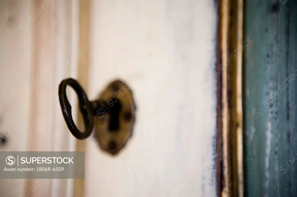 Image of aged key in keyhole.