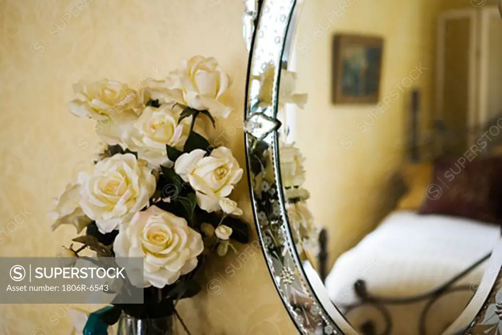 Detail of with white roses next to antique vanity mirror.