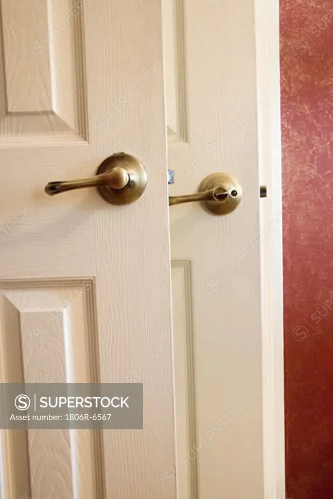 Detail of two door handles and red wall.