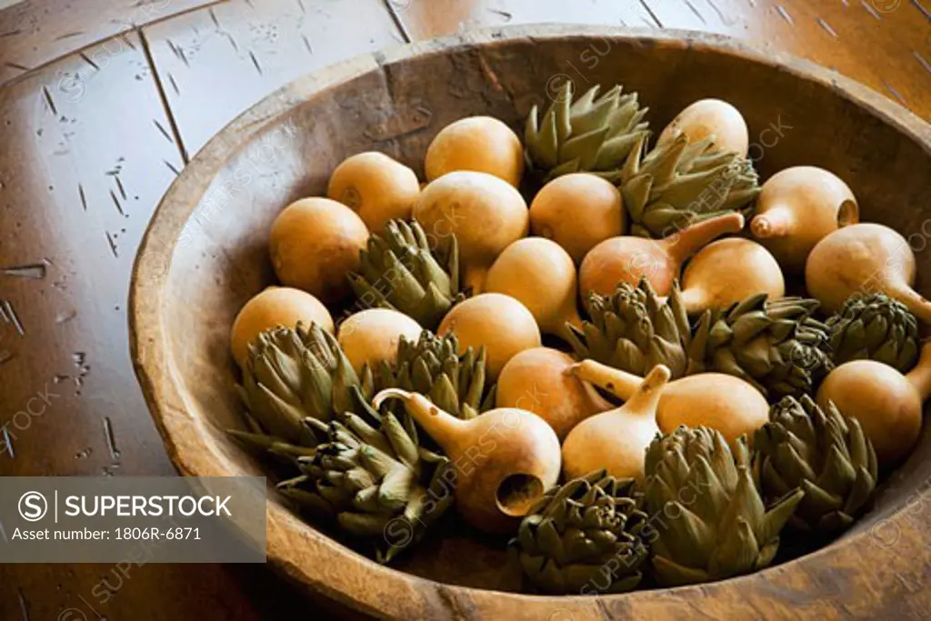 Detail of wooden bowl filled with wooden pear and artichokes.
