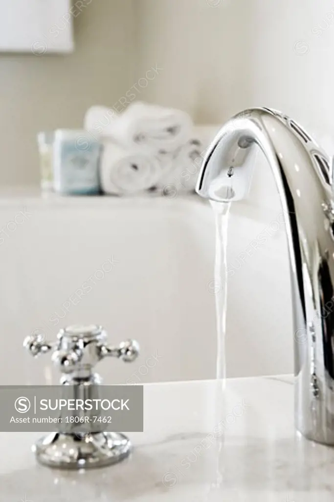 Chrome faucet with running water filling a bathtub