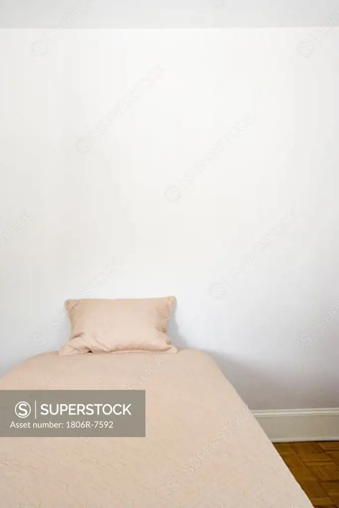 Very small bed with a single pillow