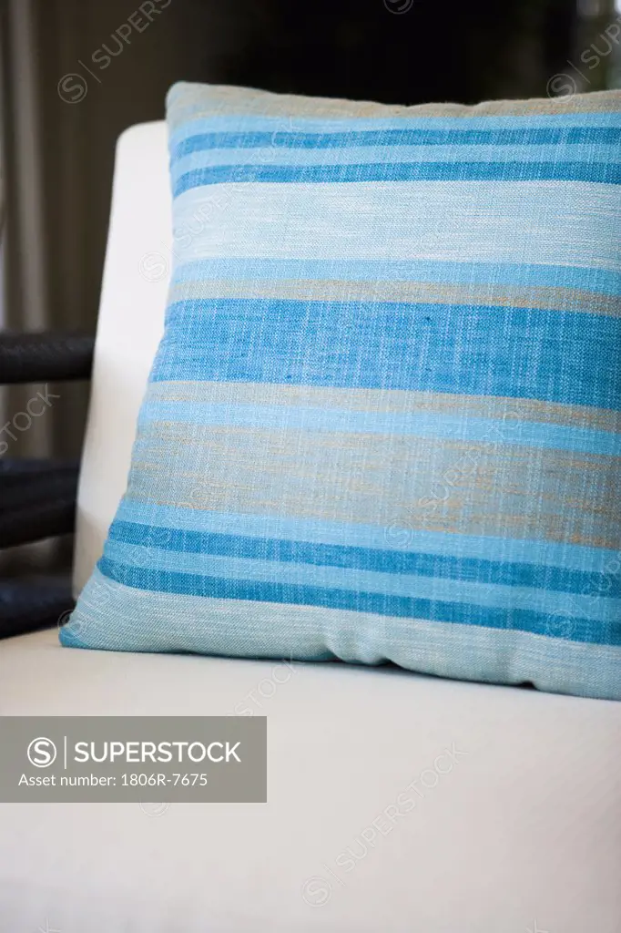 Blue striped throw pillow on white cushion chair