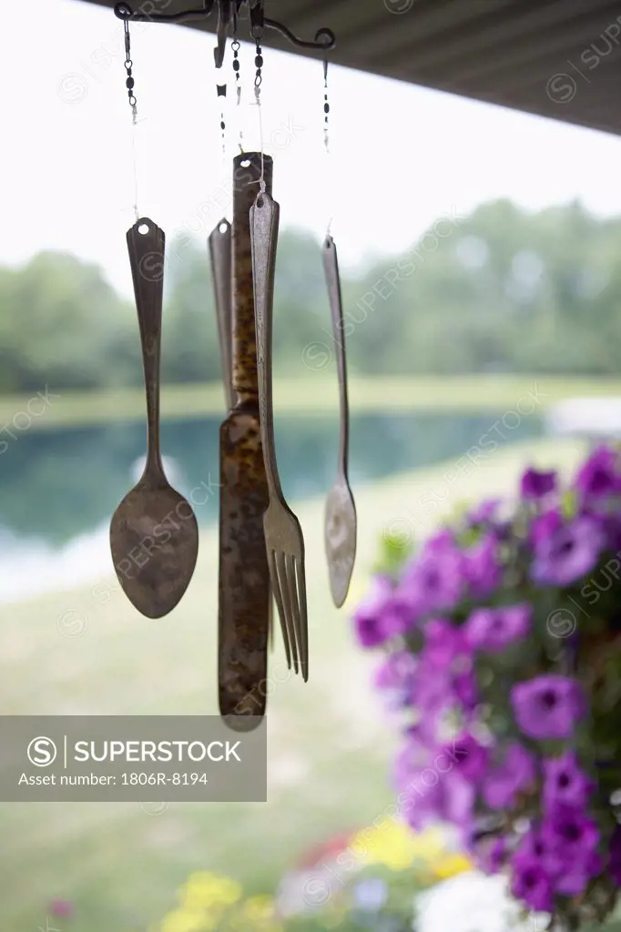 antique silverware wind chime hangs on porch of country home