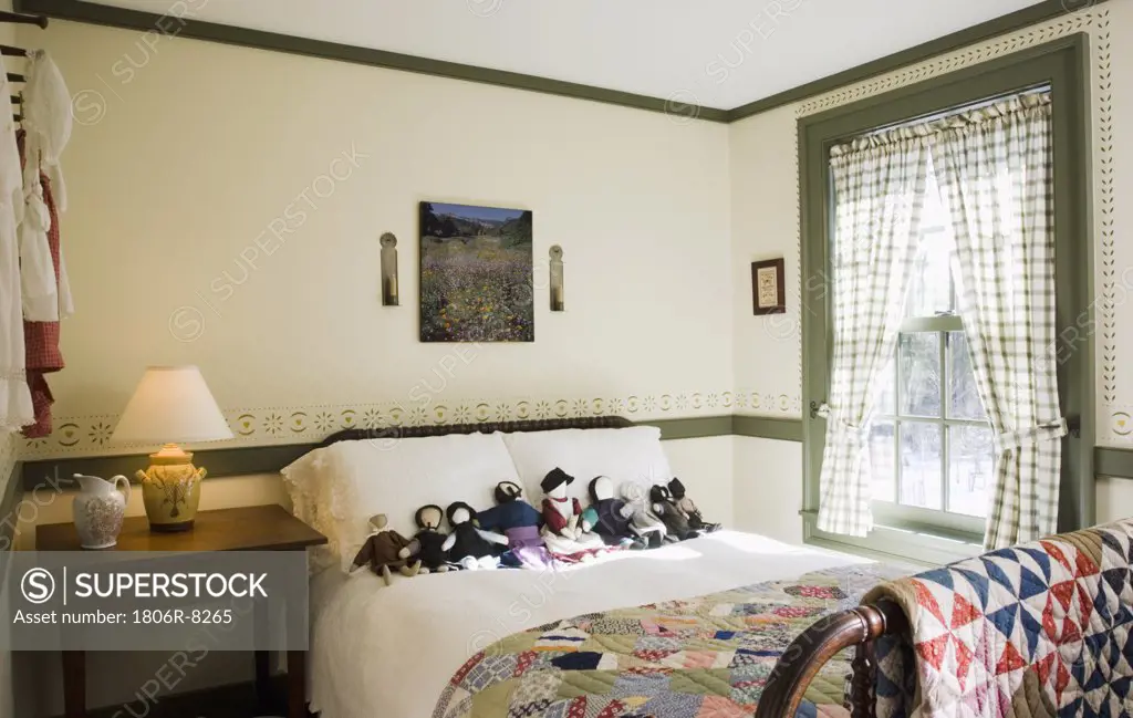 Small colonial bedroom with collection of amish dolls on bed
