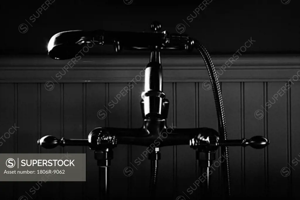 Black and white detail of bathtub faucet with detachable shower head