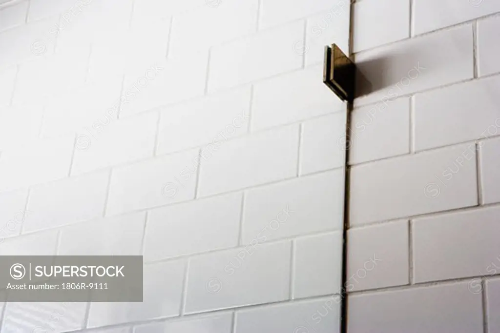 Detail tile wall with bracket holding glass shower wall