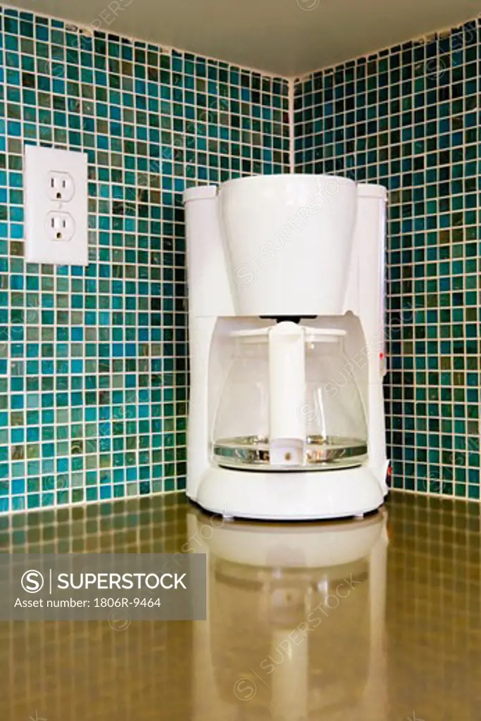 White coffee maker in corner of kitchen with colorful mosaic tile backsplash