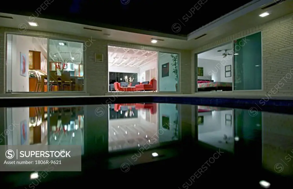 Night view in towards living room of home across pool