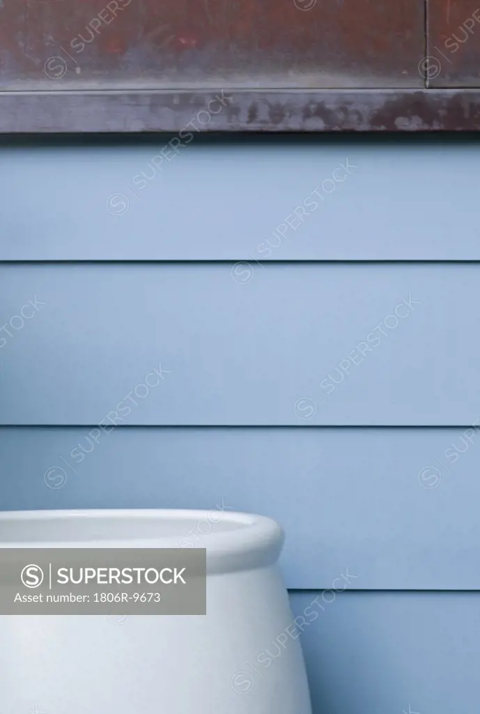 Large blue pot against blue sided home