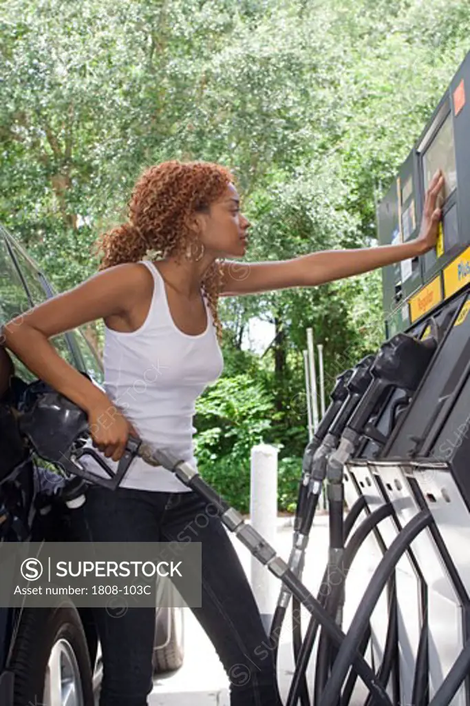 Young woman refueling a car at a gas station