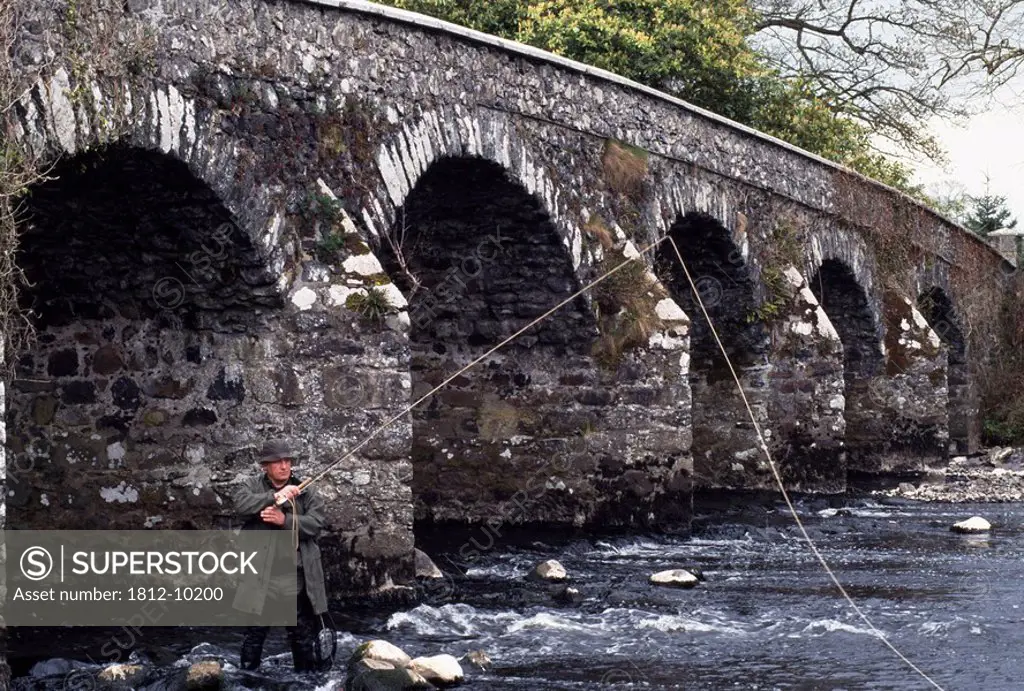 Maine River, Co Antrim, Northern Ireland, Man fly fishing under bridge
