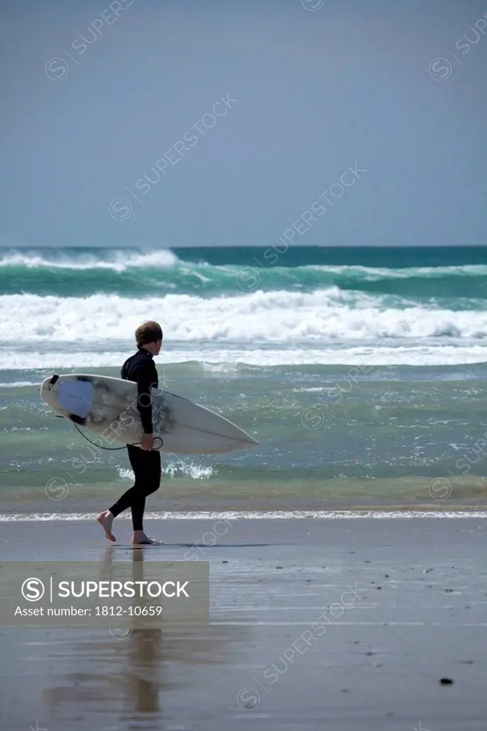 Achill Island, Co Mayo, Ireland, Surfer walking along Trawmore beach