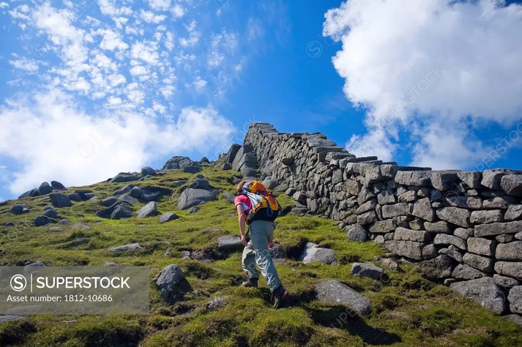 Mourne Mountains, Co Down, Ireland, Hiker beside the Mourne Wall on the slopes of Slieve Bearnagh