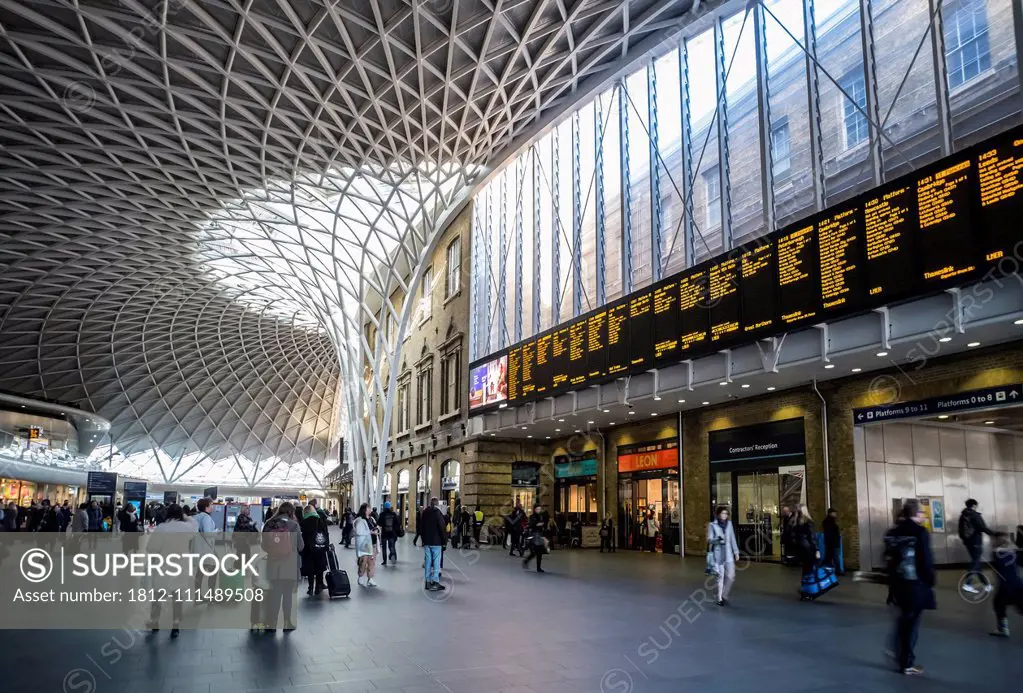 Interior of London King's Cross railway station with travellers and shops; London, England