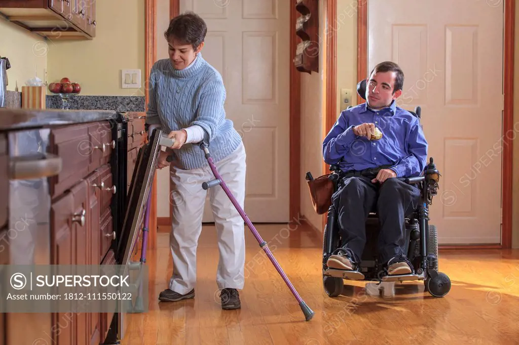 Man and woman with Cerebral Palsy preparing for lunch and using the dishwasher in their home kitchen