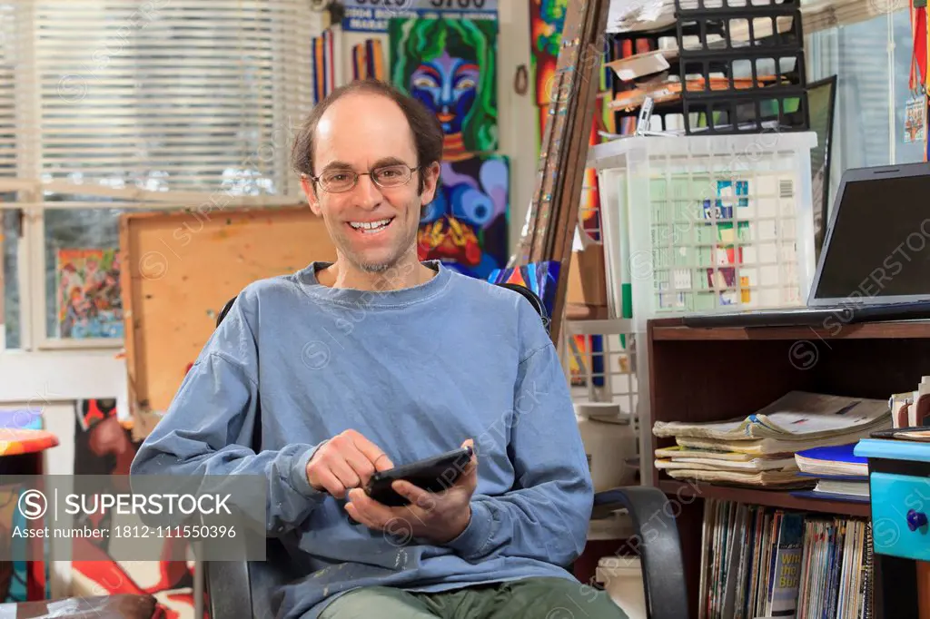 Man with Asperger's working on his tablet in his art studio