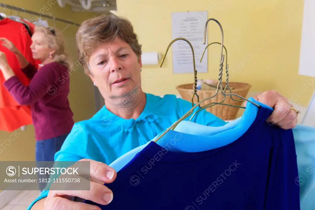 Senior women checking clothes on a hanger in a laundry room