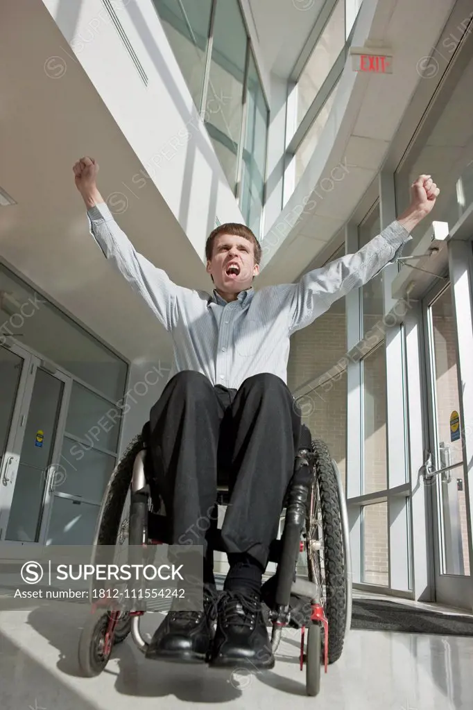 Businessman with spinal cord injury in a wheelchair with his arms raised