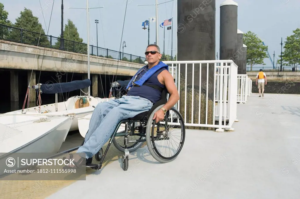 Mature man sitting in a wheelchair at a harbor for adaptive sailing